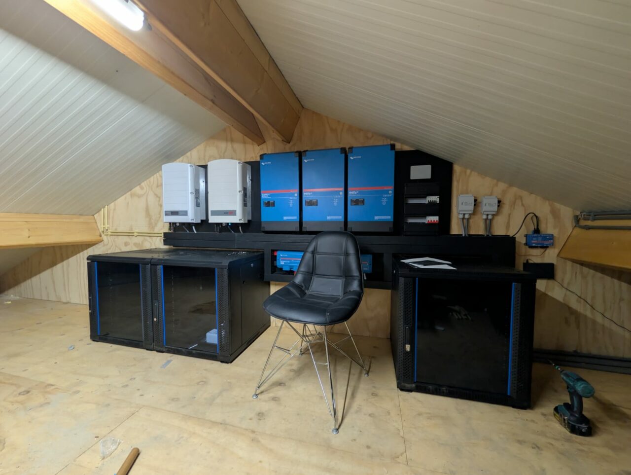 Energiesysteem met batterijrekken en Victron-omvormers onder een houten dak
